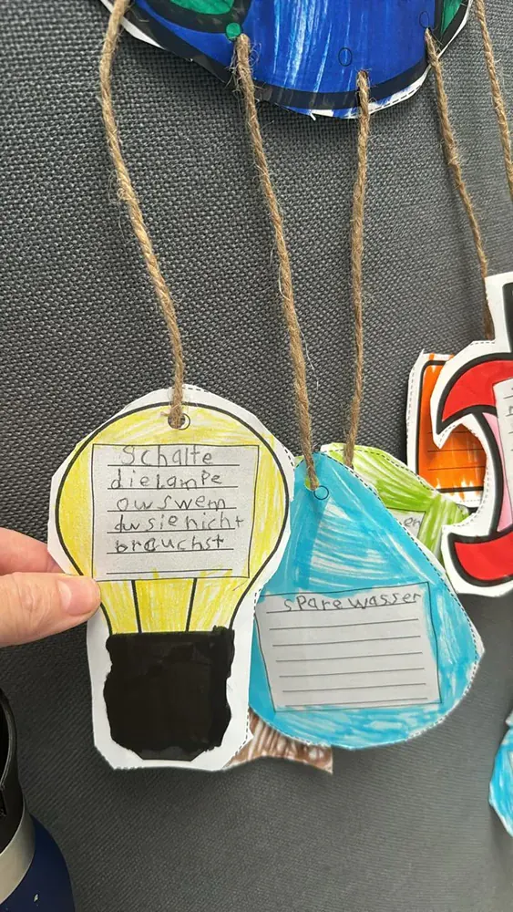 A person is holding a paper light bulb with a tag attached to it.