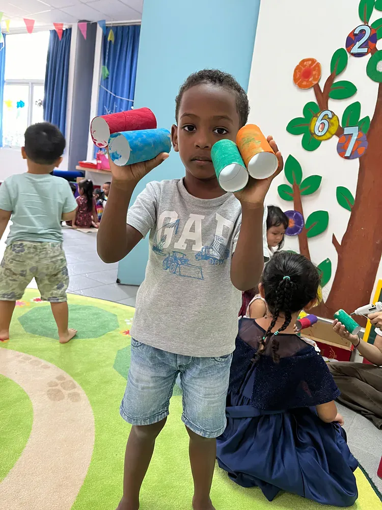 A young boy in a gap shirt is holding a stack of plastic cups.