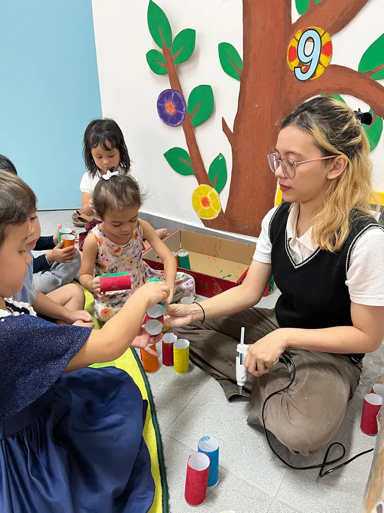 A woman is sitting on the floor playing with a group of children.