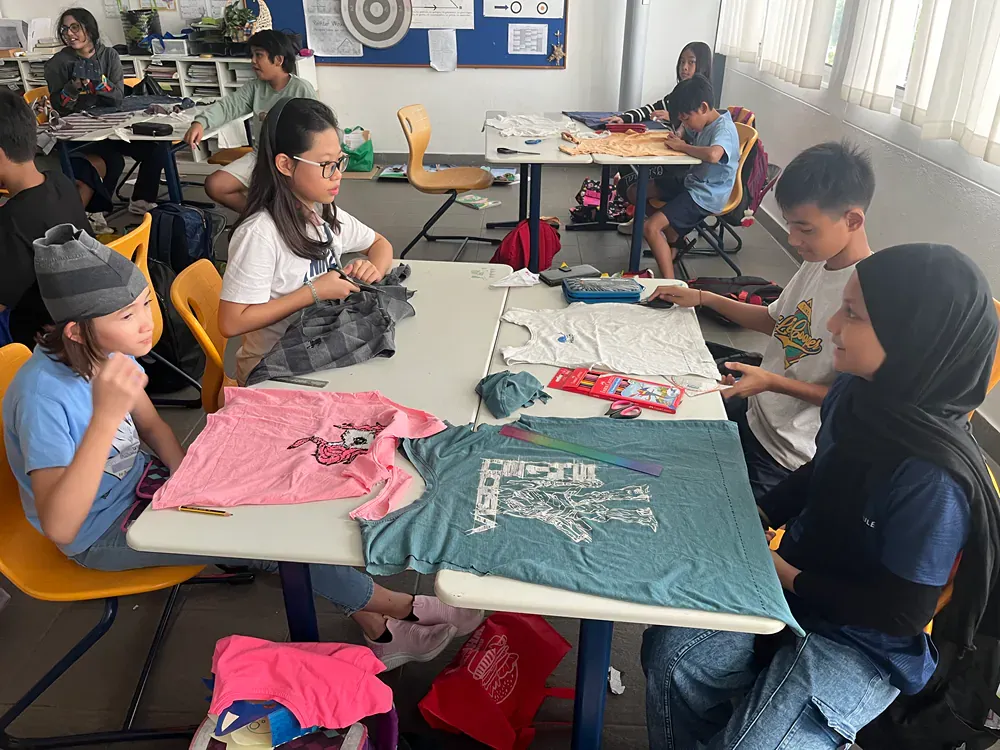 A group of children are sitting around a table in a classroom.