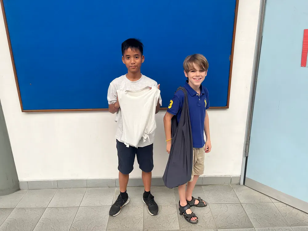 Two young boys are standing next to each other in front of a blue board.