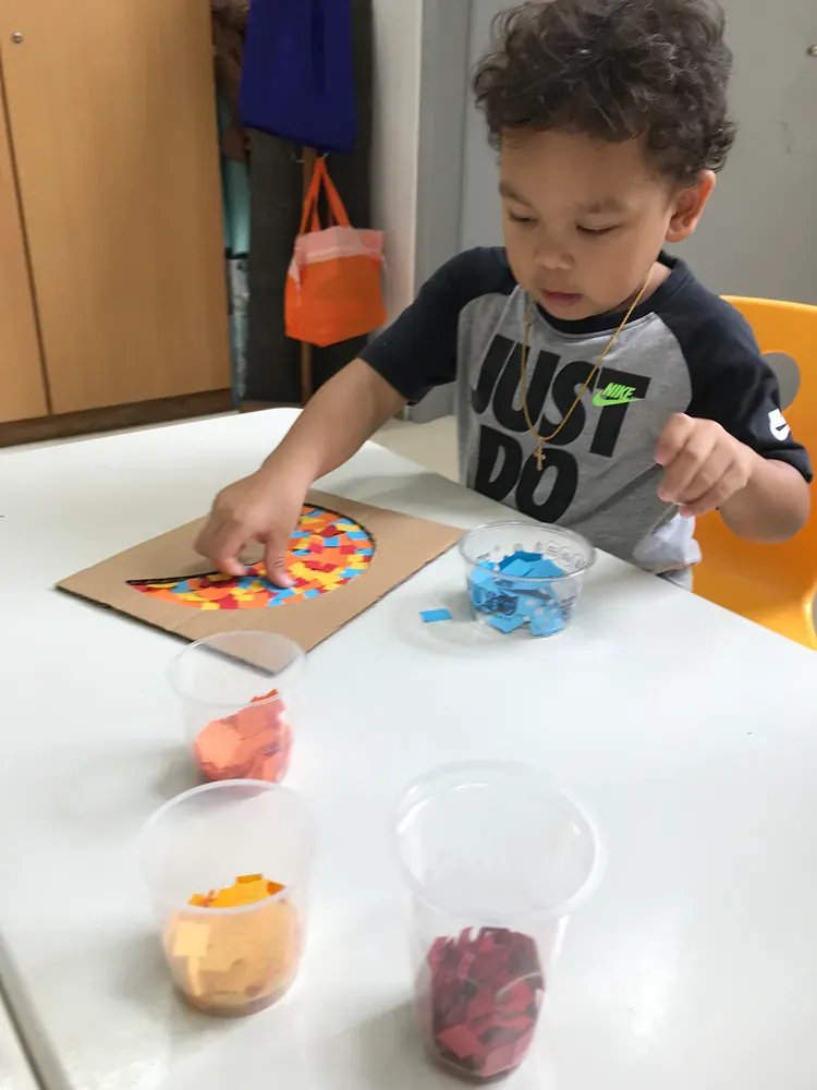 A young boy wearing a shirt that says just do is sitting at a table.