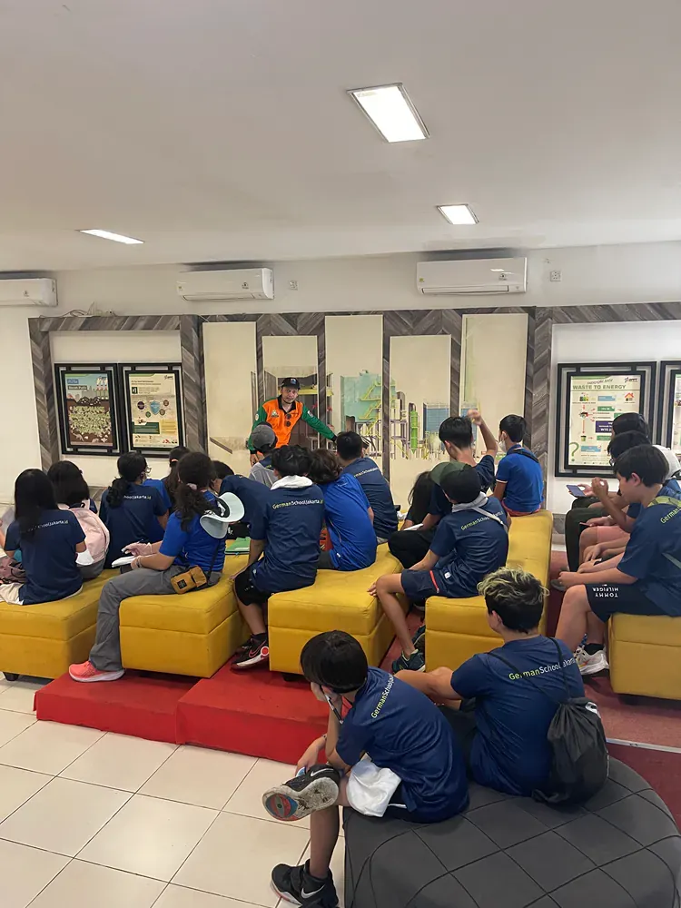 A group of people are sitting on yellow ottomans in a room.