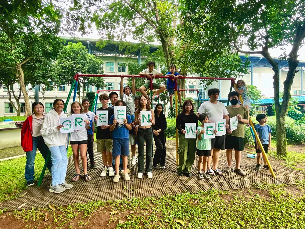 A group of people are standing on a playground holding signs that say green.