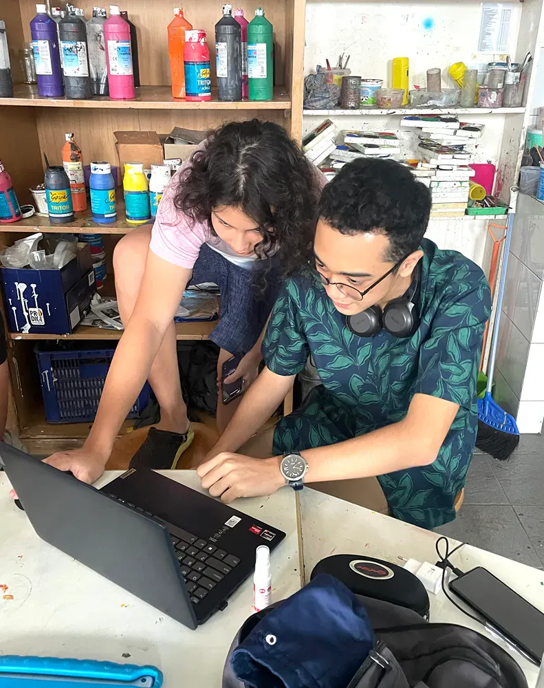 A man and a woman are looking at a laptop computer.