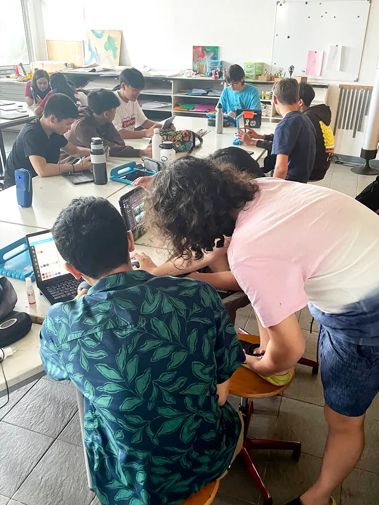 A group of people are sitting around a table with laptops.