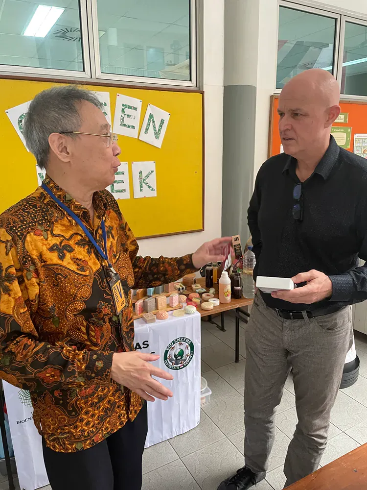 Two men are standing next to each other in a room talking.