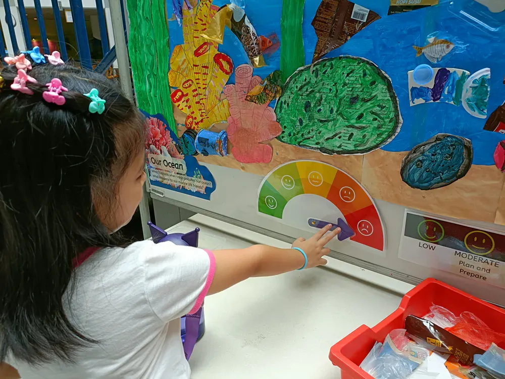 A little girl is pointing at a rainbow colored circle with smiley faces on it