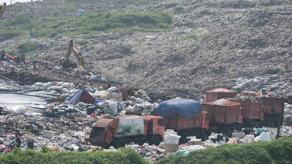 A dumpster filled with lots of trash and trucks.