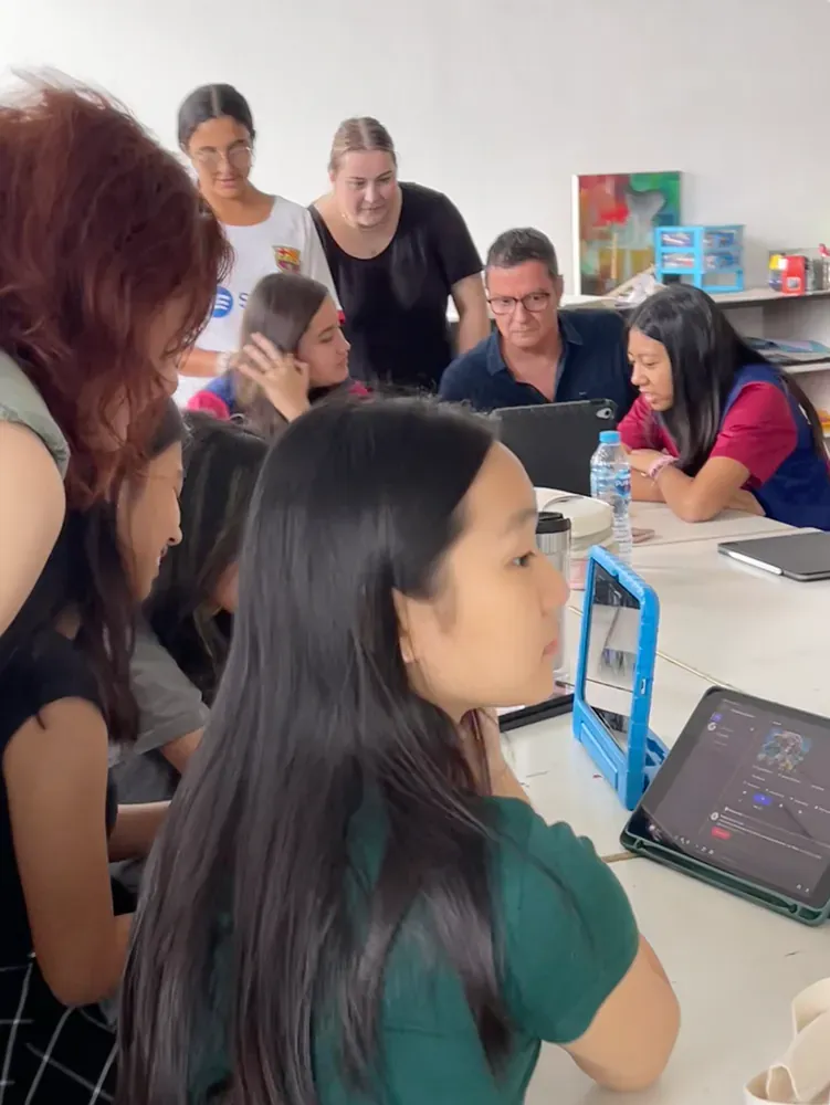 A group of people are sitting around a table looking at a tablet.