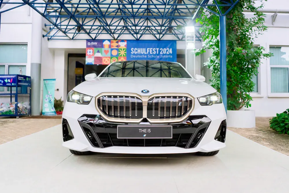 A white bmw is parked in front of a building.