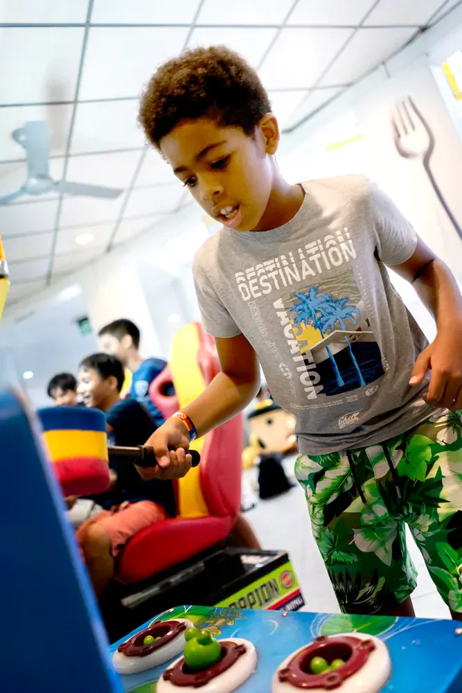 A young boy wearing a shirt that says destination is playing a game.