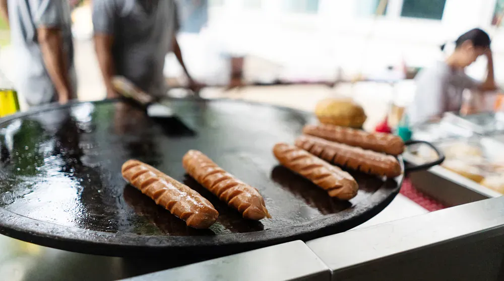 A bunch of hot dogs are being cooked on a grill.