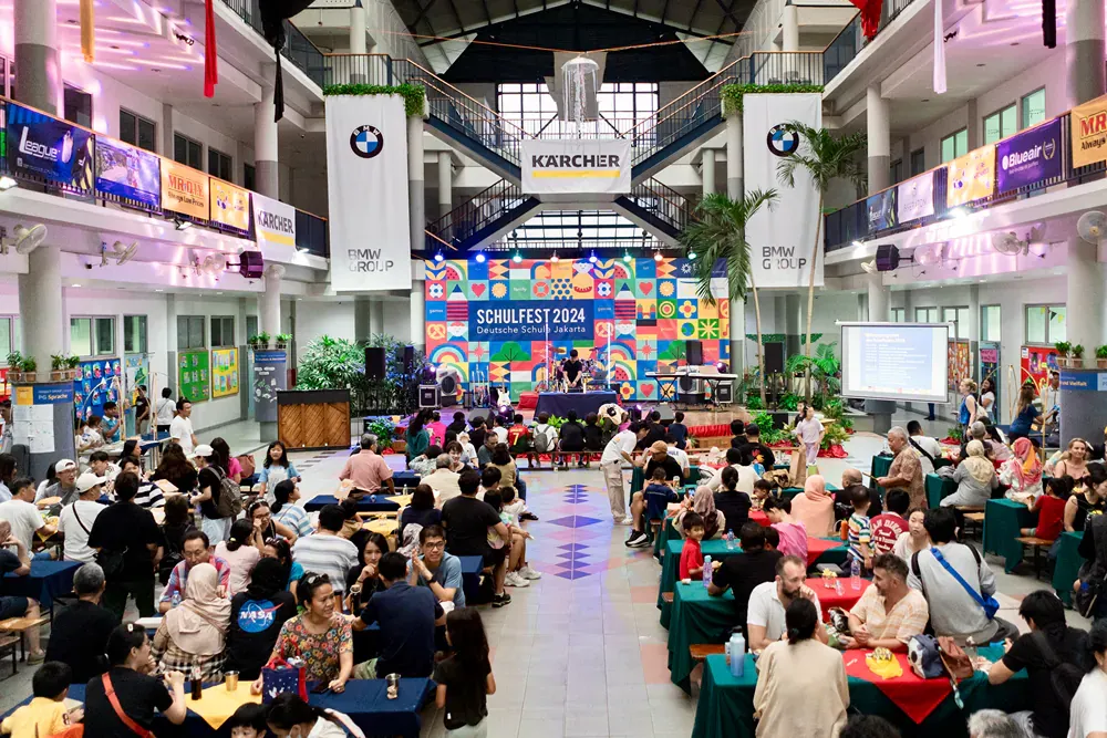 A large group of people are sitting at tables in a large building.