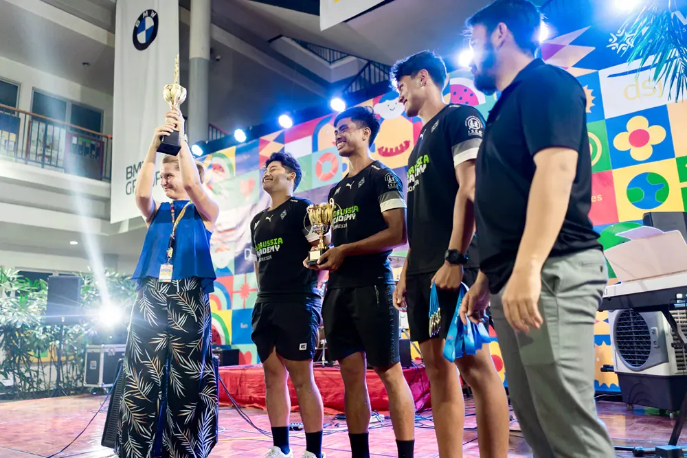 A group of men are standing on a stage holding trophies.