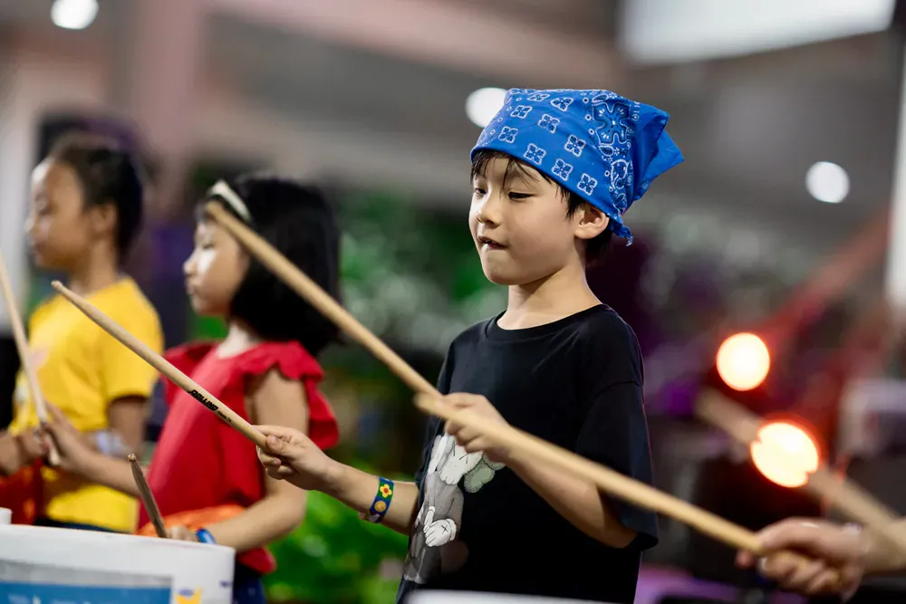 A group of children are playing drums in a room.