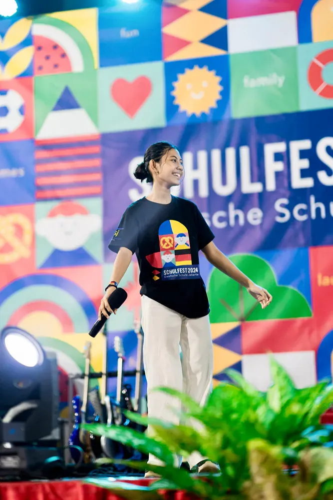 A woman is standing on a stage holding a microphone.