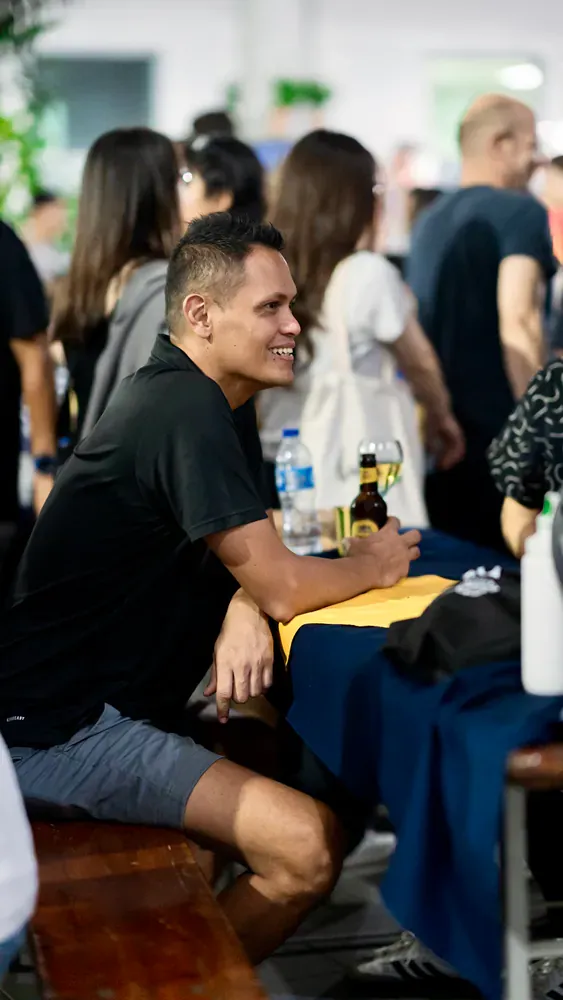 A man is sitting at a table with a bottle of beer.