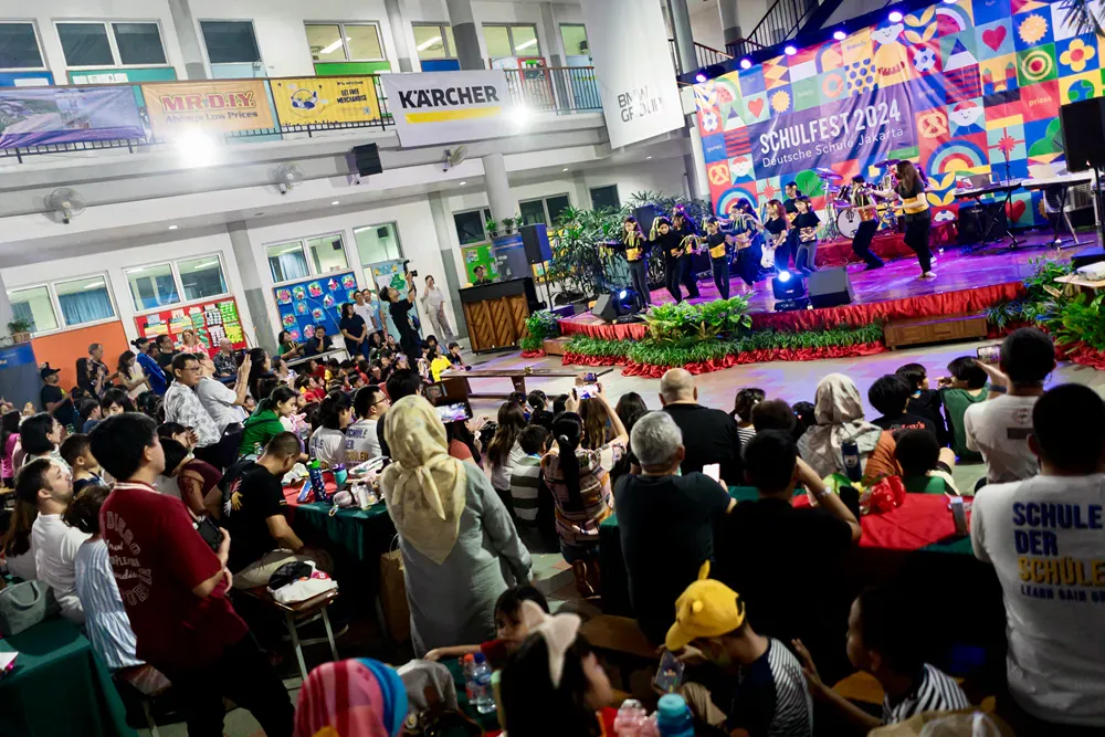 A large group of people are sitting in front of a stage at a concert.