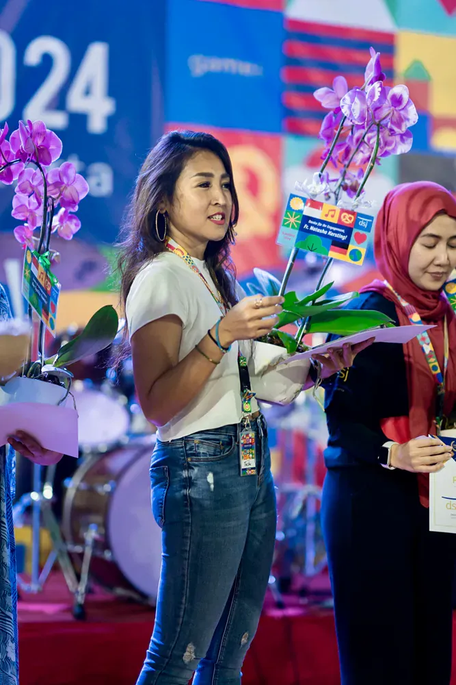 A woman is holding a bouquet of flowers in front of a drum set.