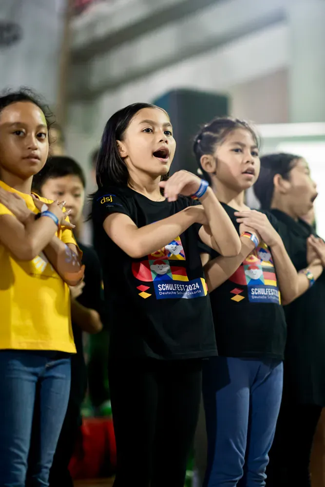 A group of young girls are singing in a choir.