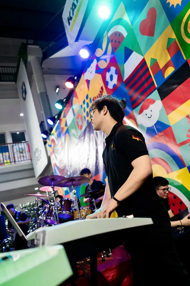 A man is playing a keyboard in front of a colorful wall.