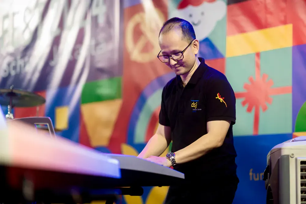 A man is playing a keyboard in front of a colorful wall.