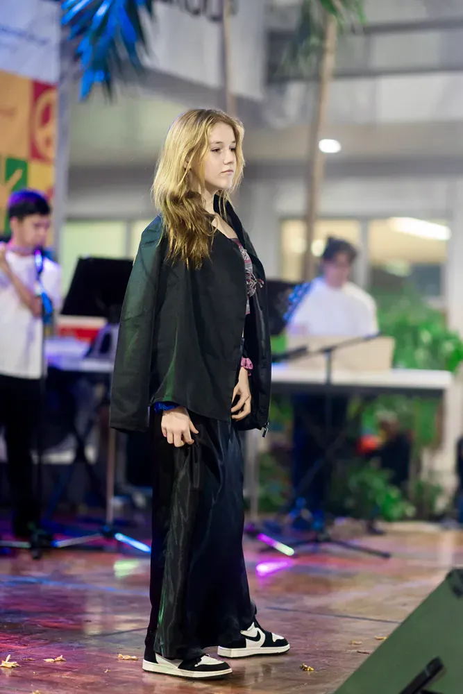 A young woman is standing on a stage in front of a microphone.