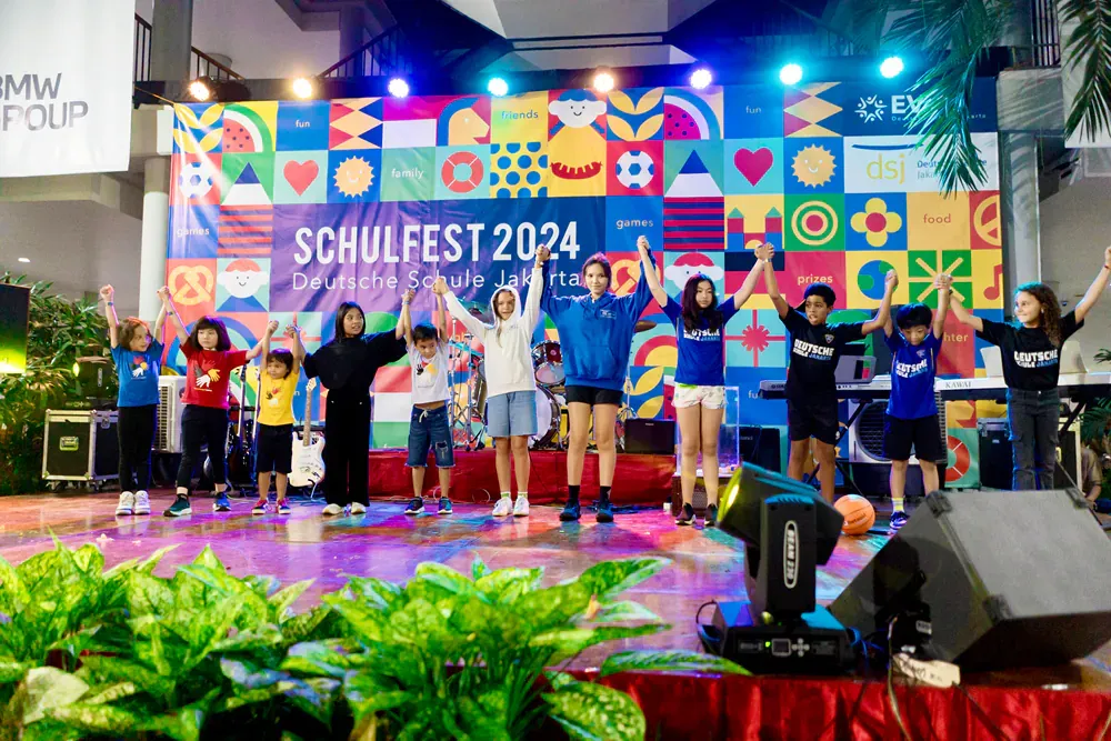 A group of people are standing on a stage with their arms in the air.