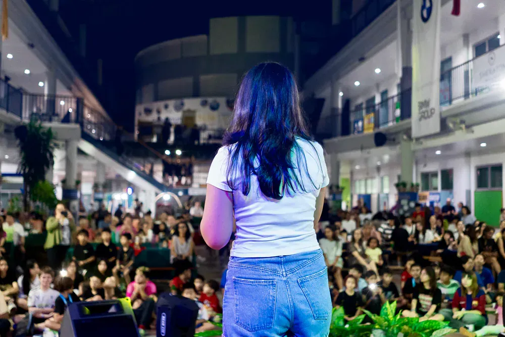 A woman is standing on a stage giving a speech to a crowd of people.