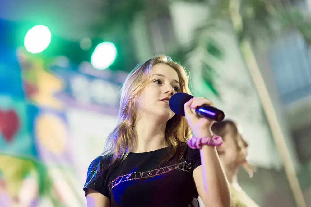 A young girl is singing into a microphone on a stage.
