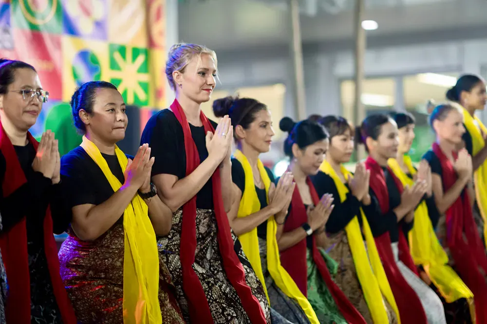 A group of women are standing in a row with their hands folded in prayer.