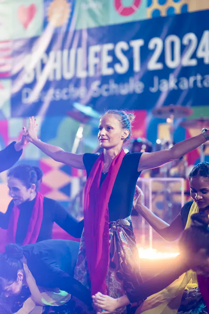 A group of people are dancing on a stage at a festival.