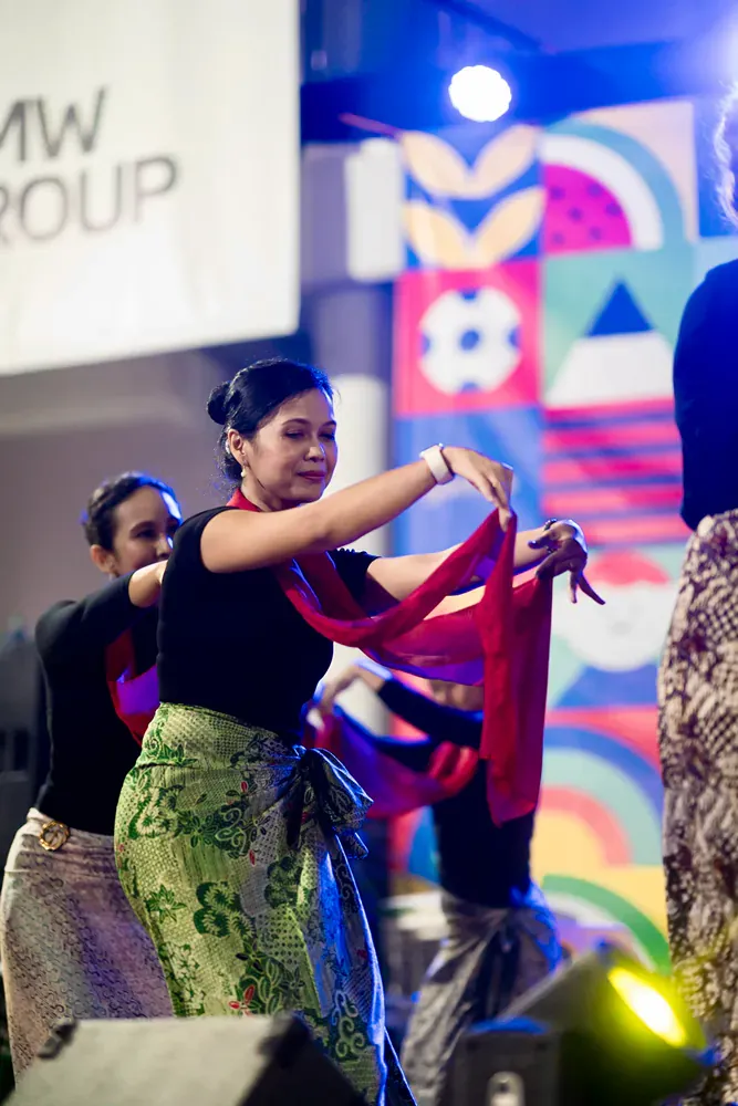 A group of women are dancing in front of a sign that says mw group