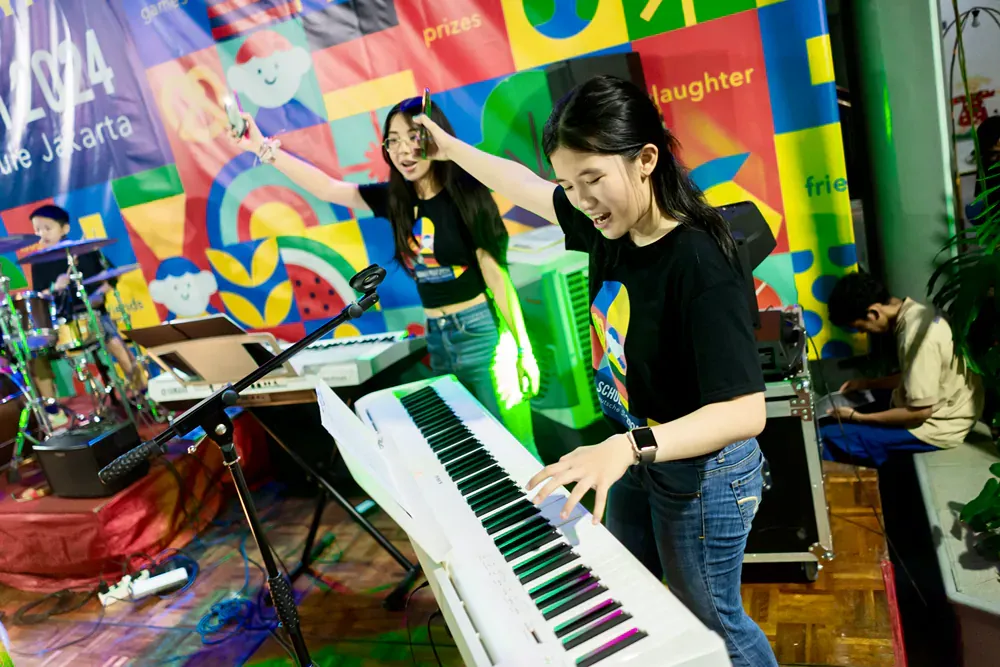 A woman is playing a piano in front of a colorful wall.