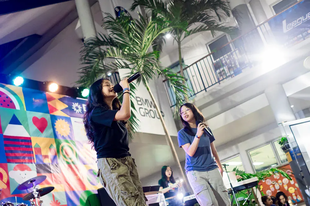 Two women are singing into microphones on a stage.
