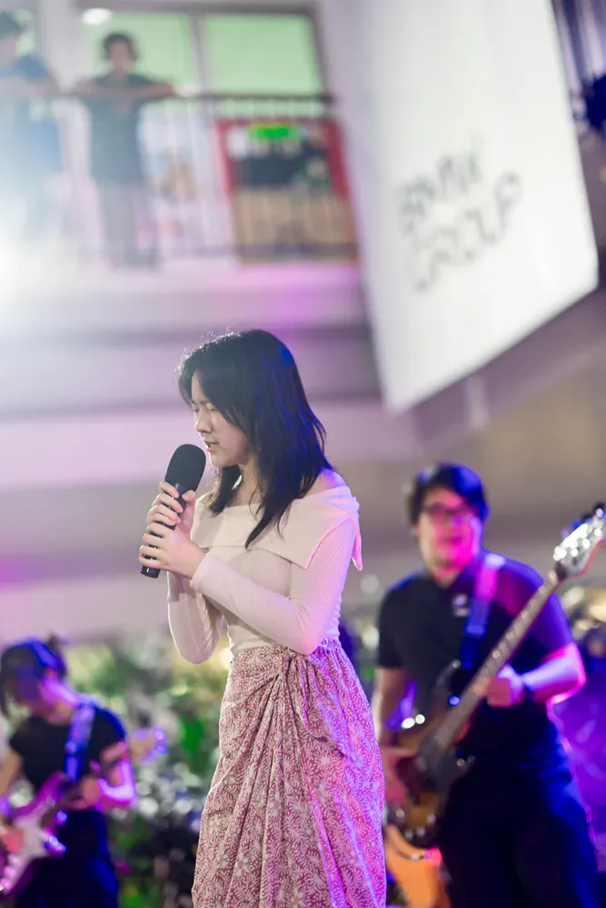 A woman is singing into a microphone while a man plays a guitar.