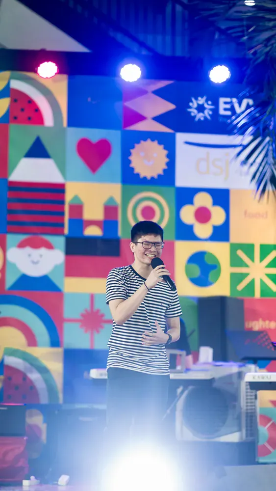 A man singing into a microphone in front of a colorful wall