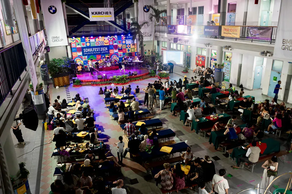 A large group of people are sitting at tables in front of a stage.