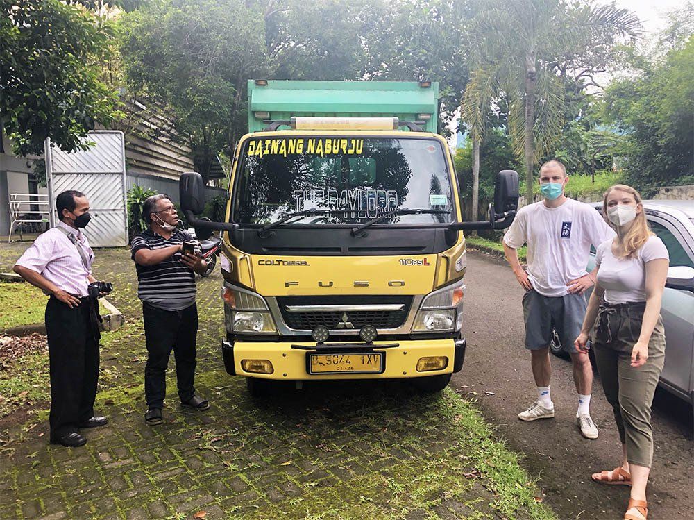A group of people are standing in front of a yellow truck.