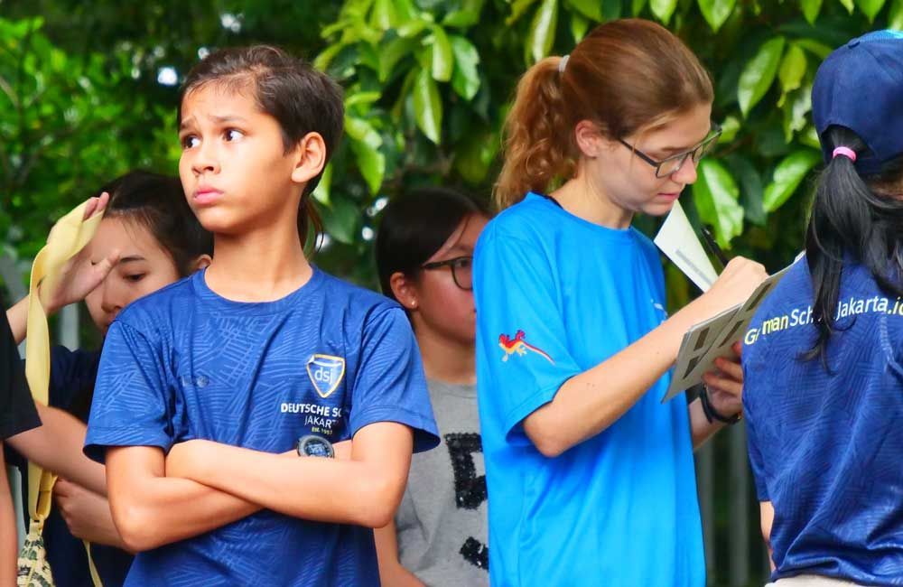 A group of children wearing blue shirts are standing in a line