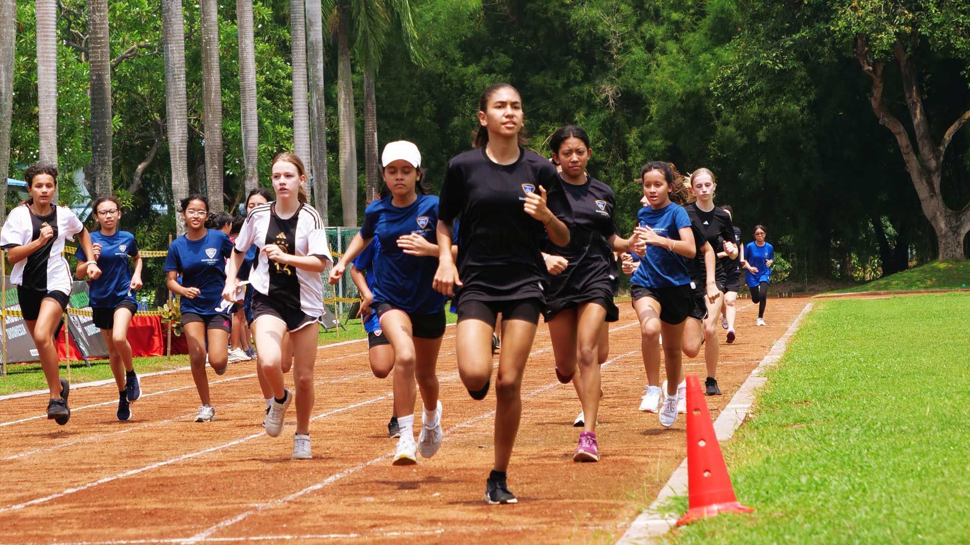 A group of young girls are running on a track.