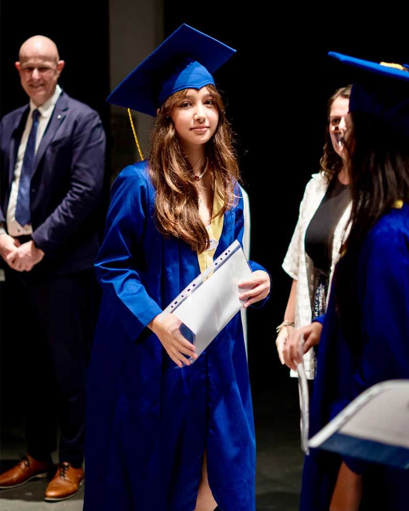 A woman in a graduation cap and gown is holding a diploma.