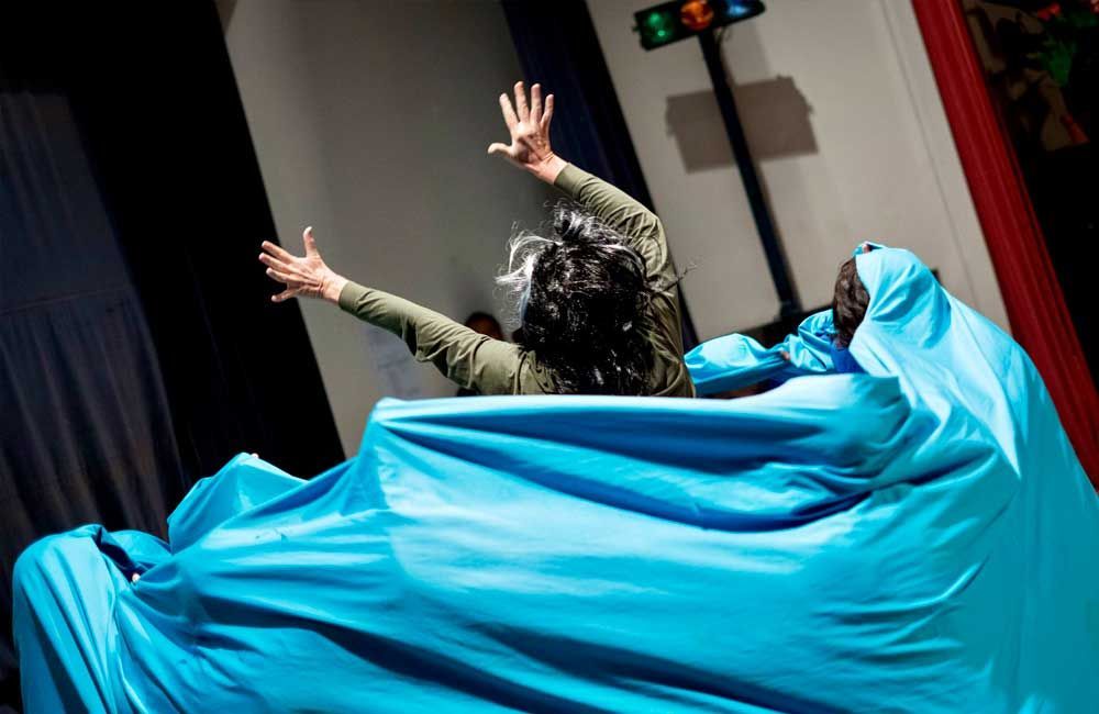 A woman is covered in a blue cloth on a stage.