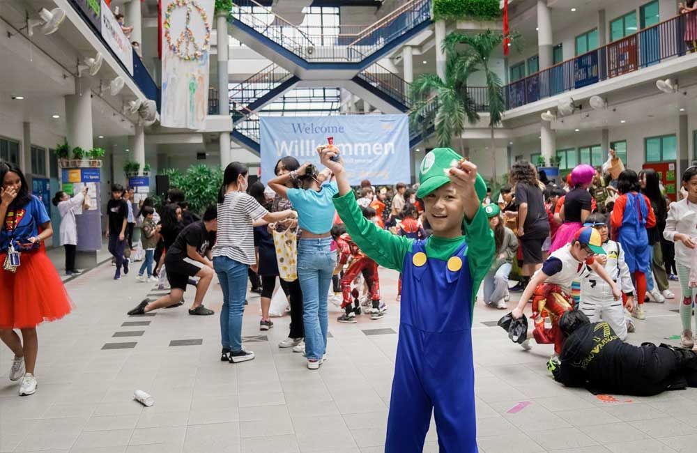 A boy in a mario costume is standing in front of a crowd of people.