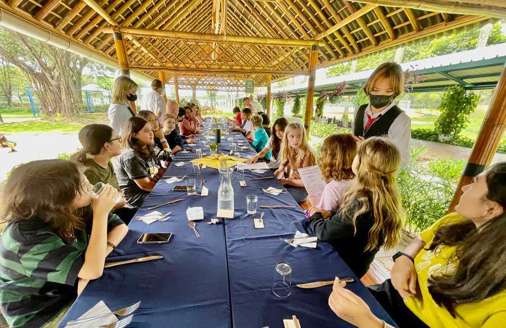 A group of people are sitting at a long table under a gazebo.