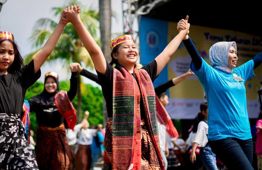 A group of people are dancing together with their arms in the air.