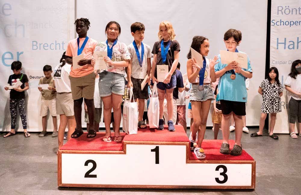 A group of children are standing on a podium with medals.