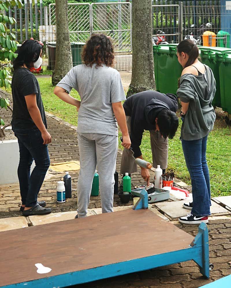 A group of people are standing around a wooden table