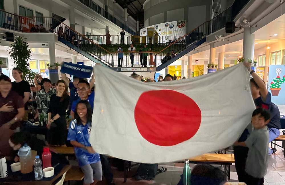 A group of people are holding a large japanese flag.